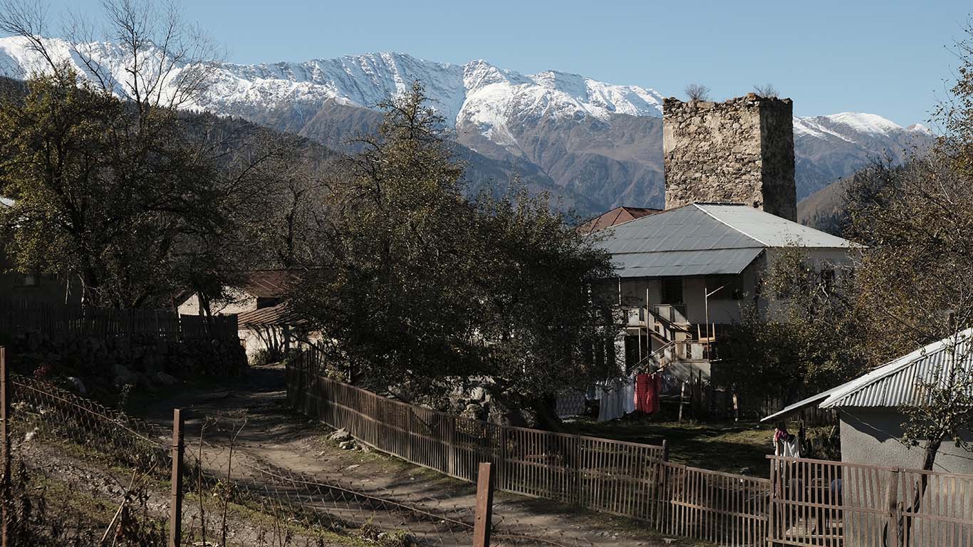 Blick auf einen Ortsteil Lentechis. Das Dorf befindet sich auf der Straße von Zugdidi nach Mestia kurz vor Mestia, dem Verwaltungszentrum Oberswanetiens. Das Bild zeigt einen verfallenden Wehrturm, vor dem sich Wohnhäuser jüngerer Entstehungszeit befinden.